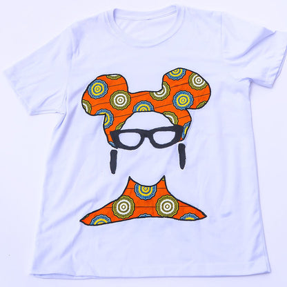 Camiseta blanca de diseño independiente hecha en Ecuador, con una ilustración frontal sutil de un rostro femenino que destaca por su turbante y cuello confeccionados con auténtica tela africana Ankara en patrón geométrico naranja, amarillo y azul, complementada con gafas y aretes negros texturizados.