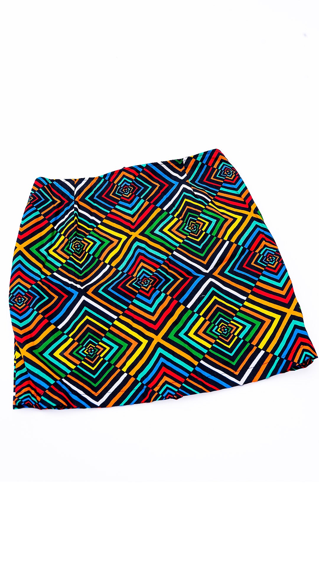 Minifalda sastrera estructurada confeccionada con auténtica tela africana Ankara, presentando un vibrante patrón geométrico de cuadrados concéntricos en capas de colores rojo, amarillo, verde, azul y negro. La falda tiene tiro alto, cierre posterior central de cremallera roja visible y corte evasé, capturada contra un fondo blanco limpio,y sifisticado